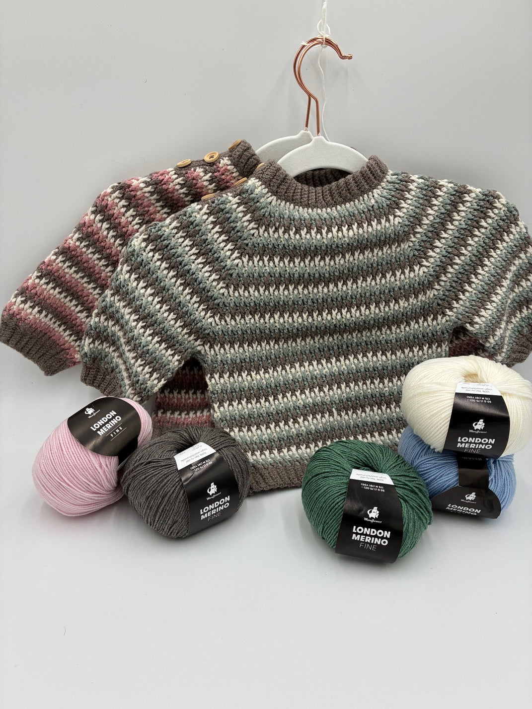 Alpine baby sweater vist i 2 forskellige farvevalg - vist sammen med nøgler af London merino fine.