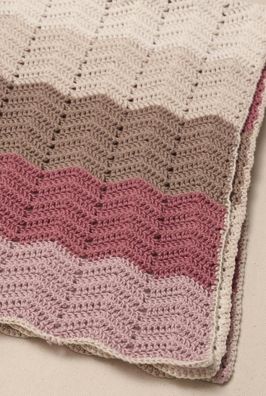 Hæklet babytæppe med zigzagstriber i råhvide, beige, brune og rosa nuancer, hæklet i Anyday Cotton 8/4 Colorbag fra Mayflower.